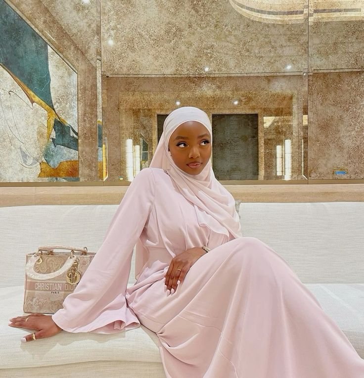 Rodia in pale pink, reclining on a white sofa in a mirrored room.